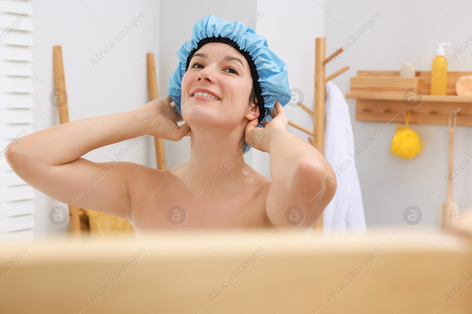 Photo of Woman wearing blue shower cap in bathroom