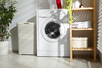 Photo of Wicker laundry basket, washing machine and detergents in bathroom