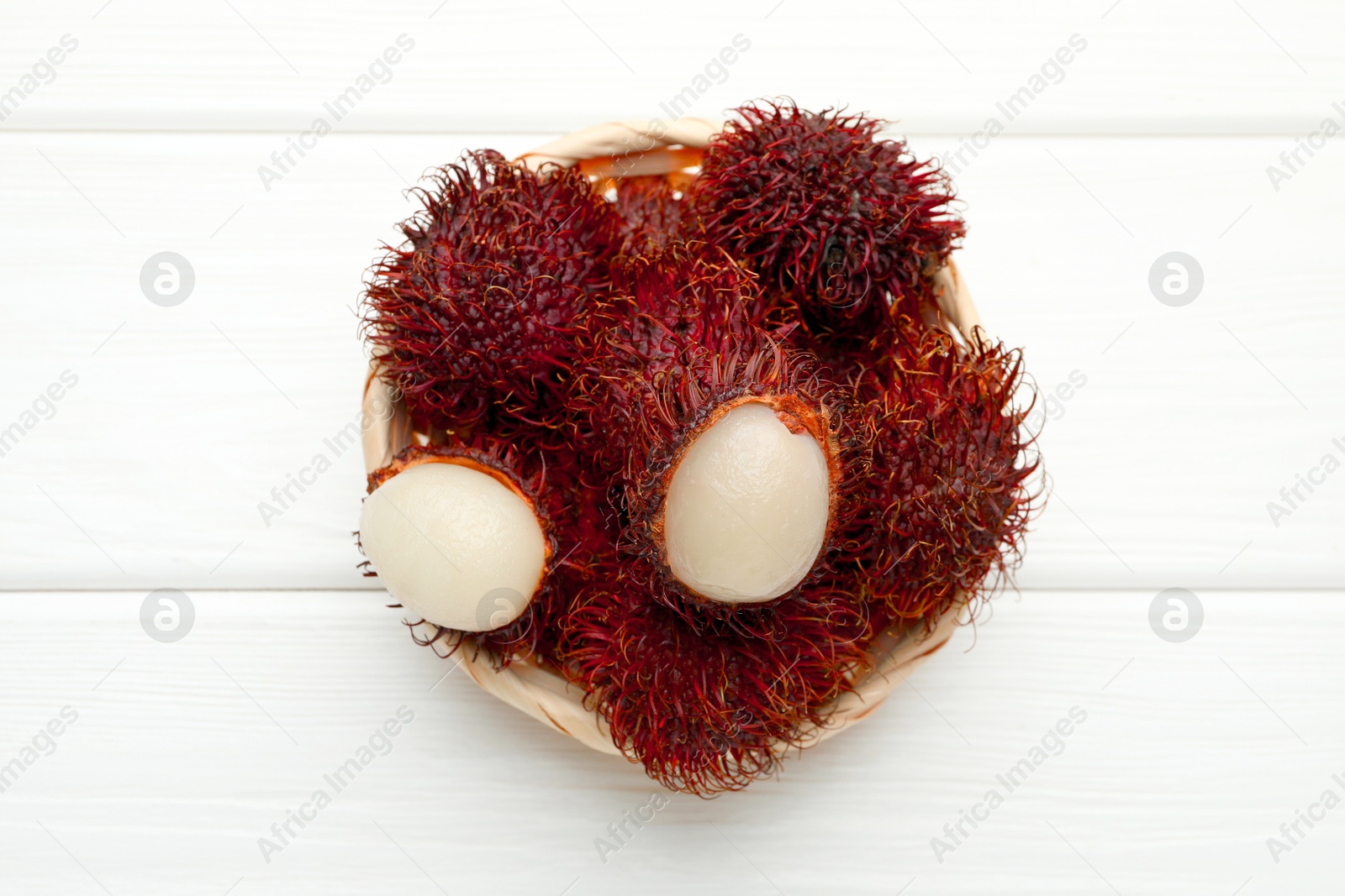 Photo of Delicious ripe rambutans on white wooden table, top view