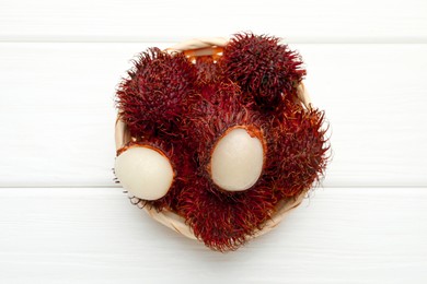 Photo of Delicious ripe rambutans on white wooden table, top view