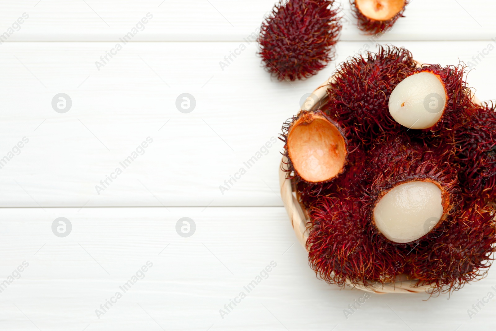 Photo of Delicious ripe rambutans on white wooden table, top view. Space for text