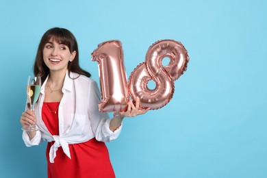 Photo of Coming of age party - 18th birthday. Young woman with glass of wine holding number shaped balloons on light blue background, space for text