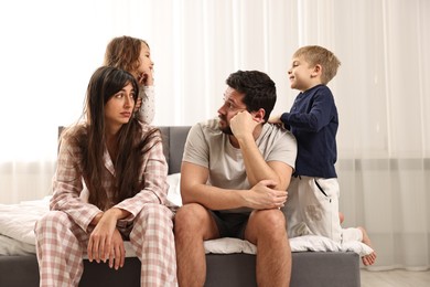 Photo of Playful children and their overwhelmed parents on bed at home