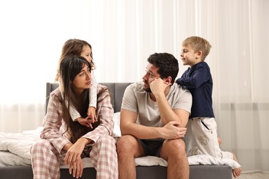 Photo of Playful children and their overwhelmed parents on bed at home