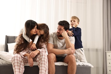 Photo of Playful children and their overwhelmed parents on bed at home