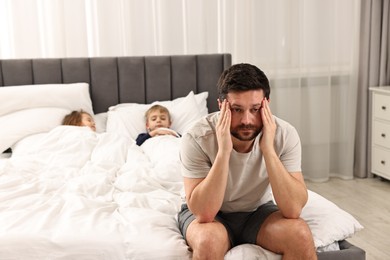 Photo of Overwhelmed father and his children on bed at home