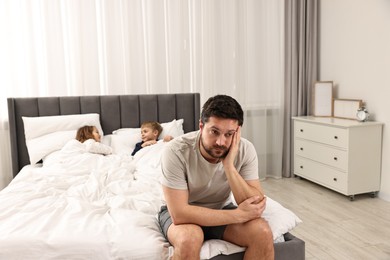 Overwhelmed father and his naughty children on bed at home