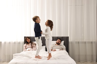 Photo of Overwhelmed parents and their playful children on bed at home