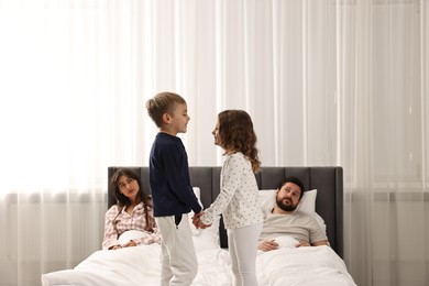 Photo of Overwhelmed parents and their playful children on bed at home