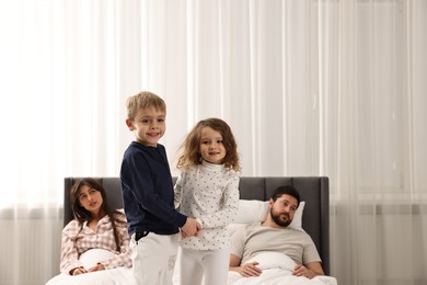 Photo of Overwhelmed parents and their playful children on bed at home