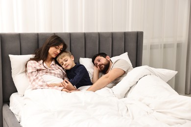 Photo of Overwhelmed parents with their son in bed at home