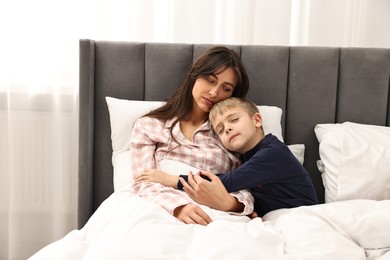 Overwhelmed mother with her son in bed at home