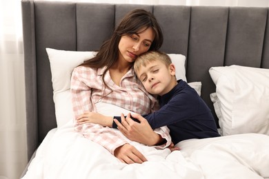 Overwhelmed mother with her son in bed at home