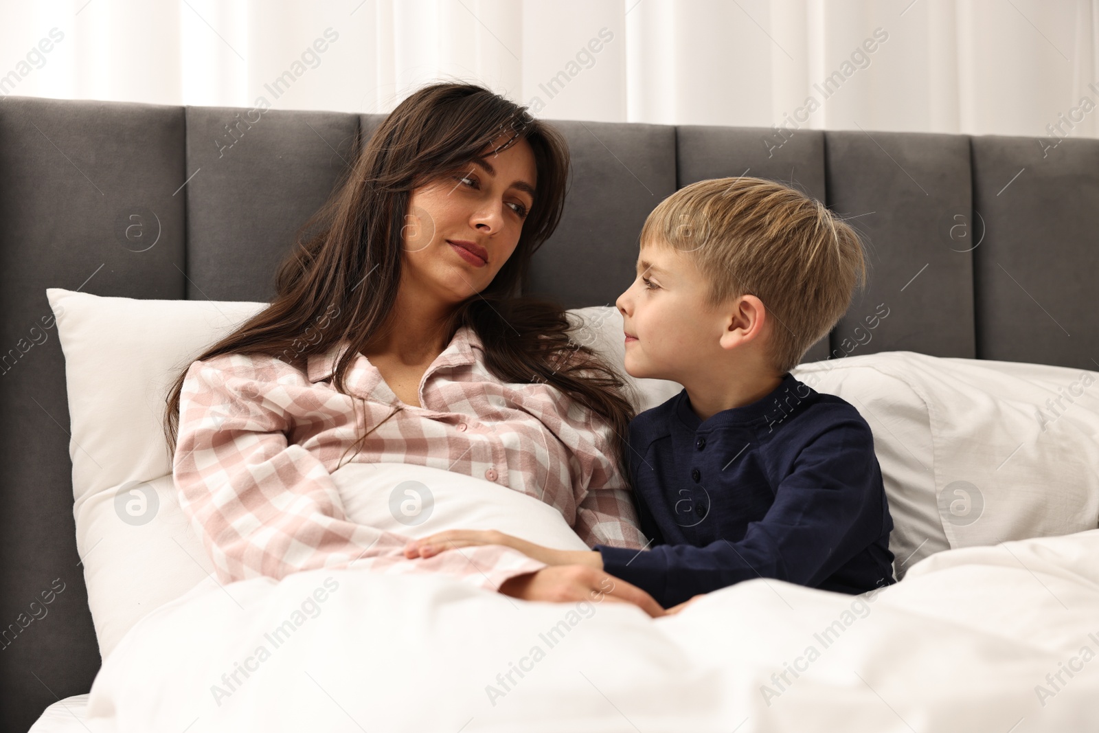 Photo of Overwhelmed mother with her son in bed at home