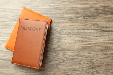 Photo of Passports in color covers on wooden table, top view. Space for text