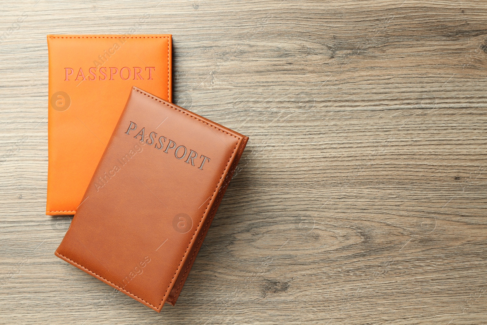 Photo of Passports in color covers on wooden table, top view. Space for text