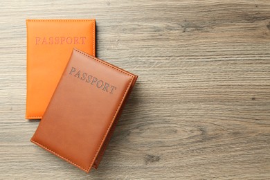 Photo of Passports in color covers on wooden table, top view. Space for text