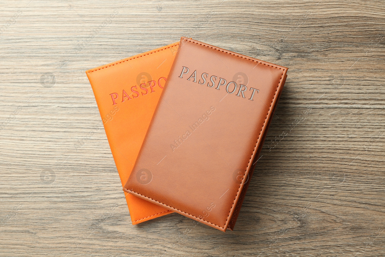 Photo of Passports in color covers on wooden table, top view