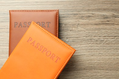 Photo of Passports in color covers on wooden table, top view. Space for text