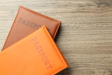 Photo of Passports in color covers on wooden table, top view. Space for text