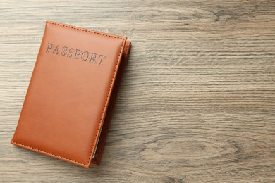 Photo of Passport in brown cover on wooden table, top view. Space for text