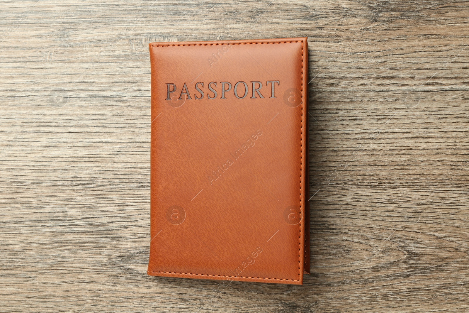 Photo of Passport in brown cover on wooden table, top view