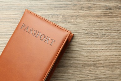 Photo of Passport in brown cover on wooden table, top view. Space for text