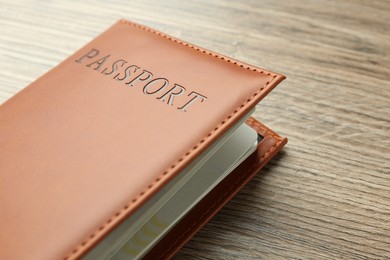 Photo of Passport in brown cover on wooden table, closeup