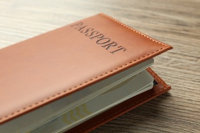 Photo of Passport in brown cover on wooden table, closeup