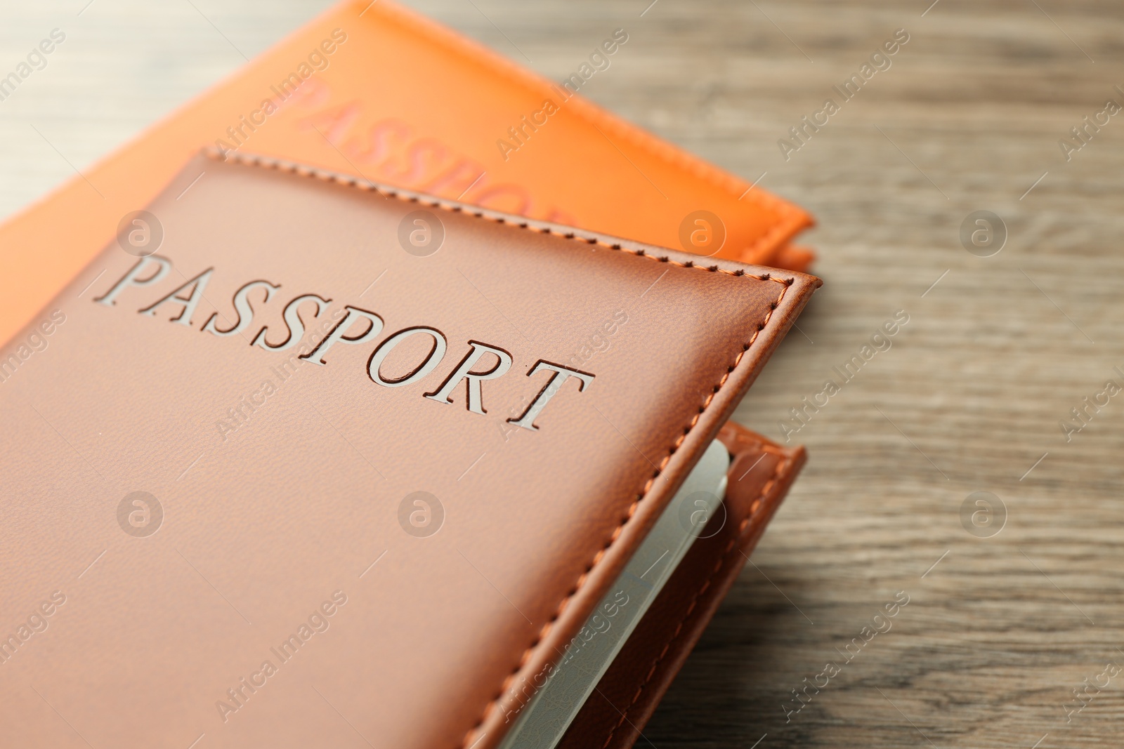 Photo of Passports in color covers on wooden table, closeup