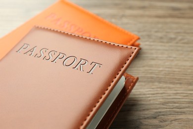 Photo of Passports in color covers on wooden table, closeup