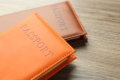 Photo of Passports in color covers on wooden table, closeup