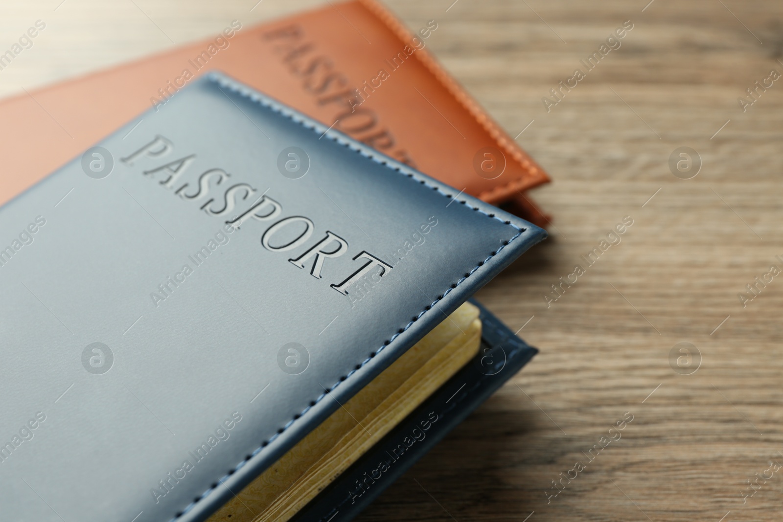 Photo of Passports in color covers on wooden table, closeup