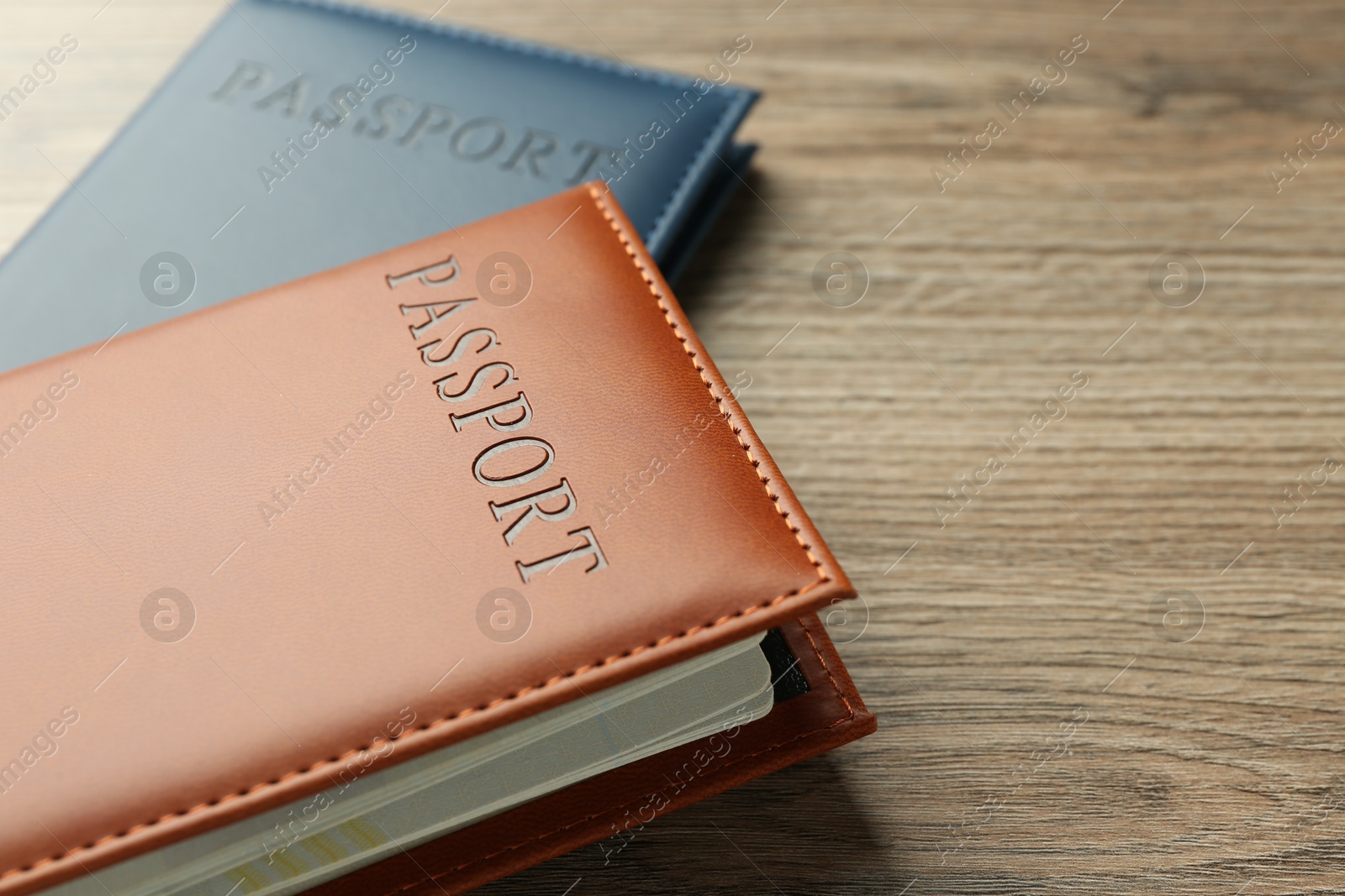 Photo of Passports in color covers on wooden table, closeup. Space for text