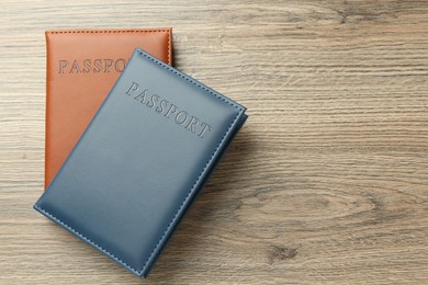 Photo of Passports in color covers on wooden table, top view. Space for text