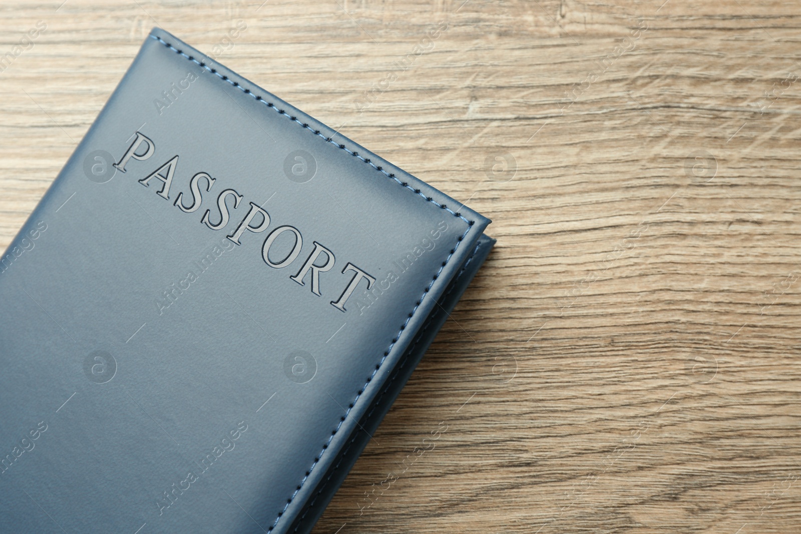 Photo of Passport in blue cover on wooden table, top view. Space for text