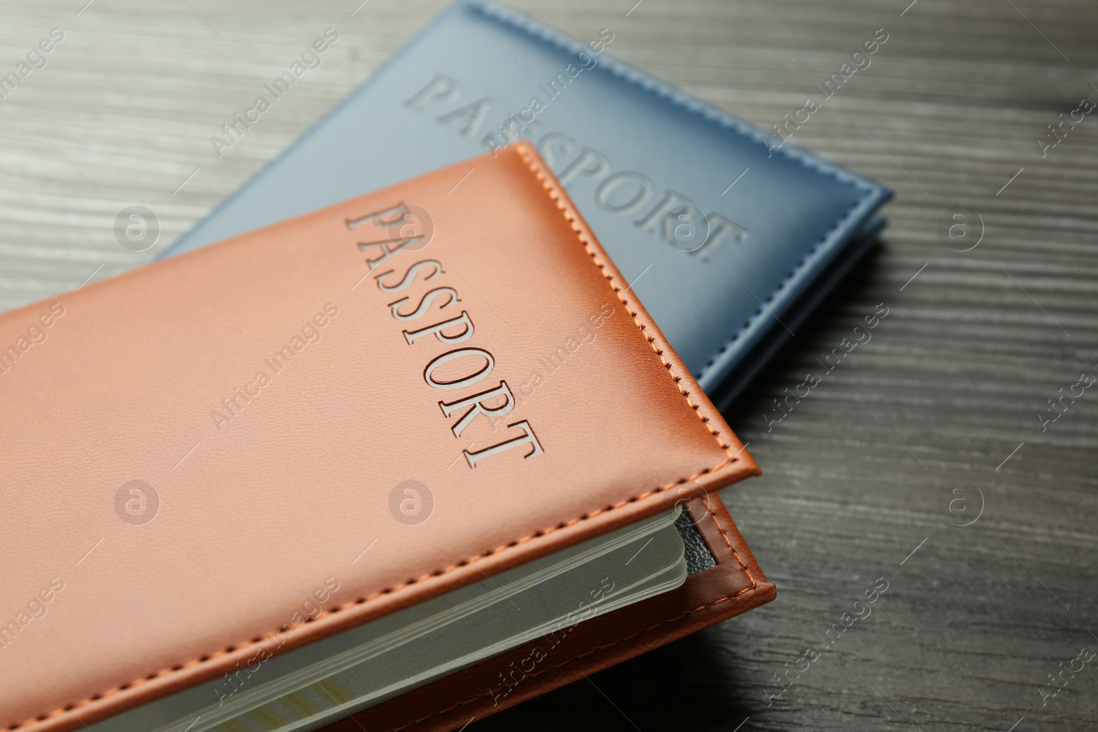 Photo of Passports in color covers on wooden table, closeup