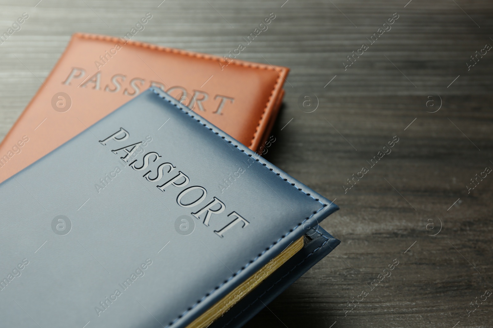 Photo of Passports in color covers on wooden table, closeup. Space for text