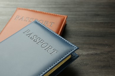 Photo of Passports in color covers on wooden table, closeup. Space for text