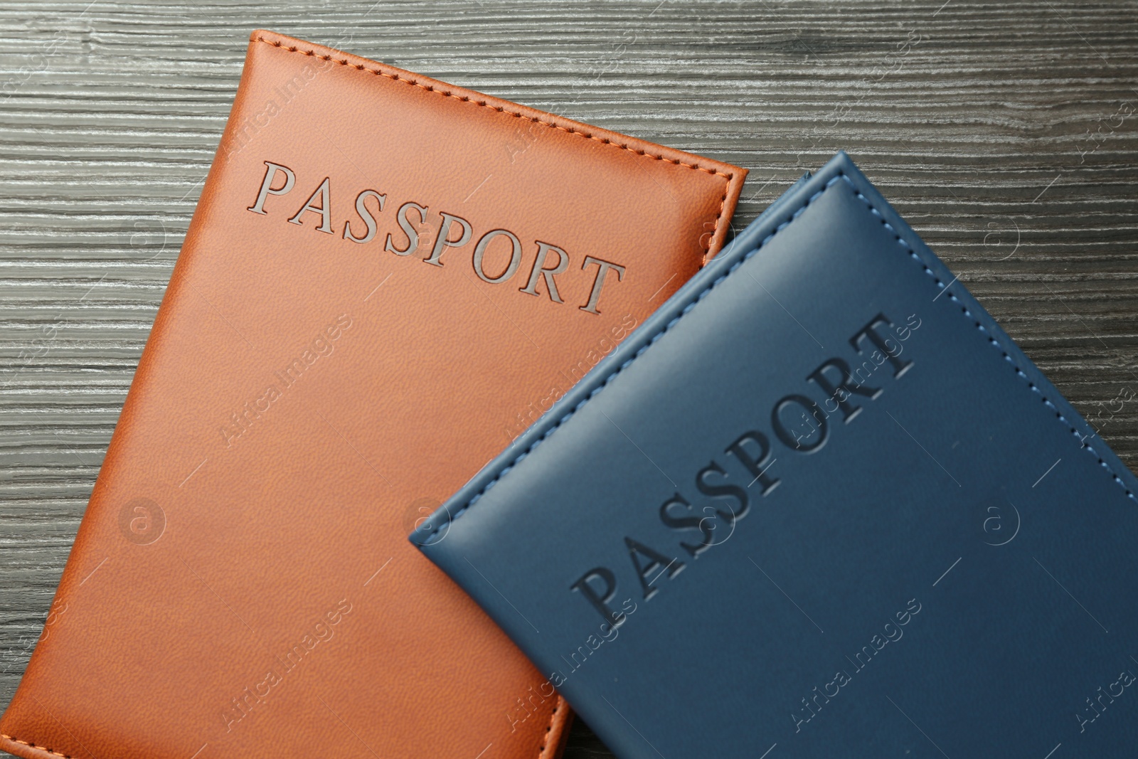 Photo of Passports in color covers on wooden table, top view