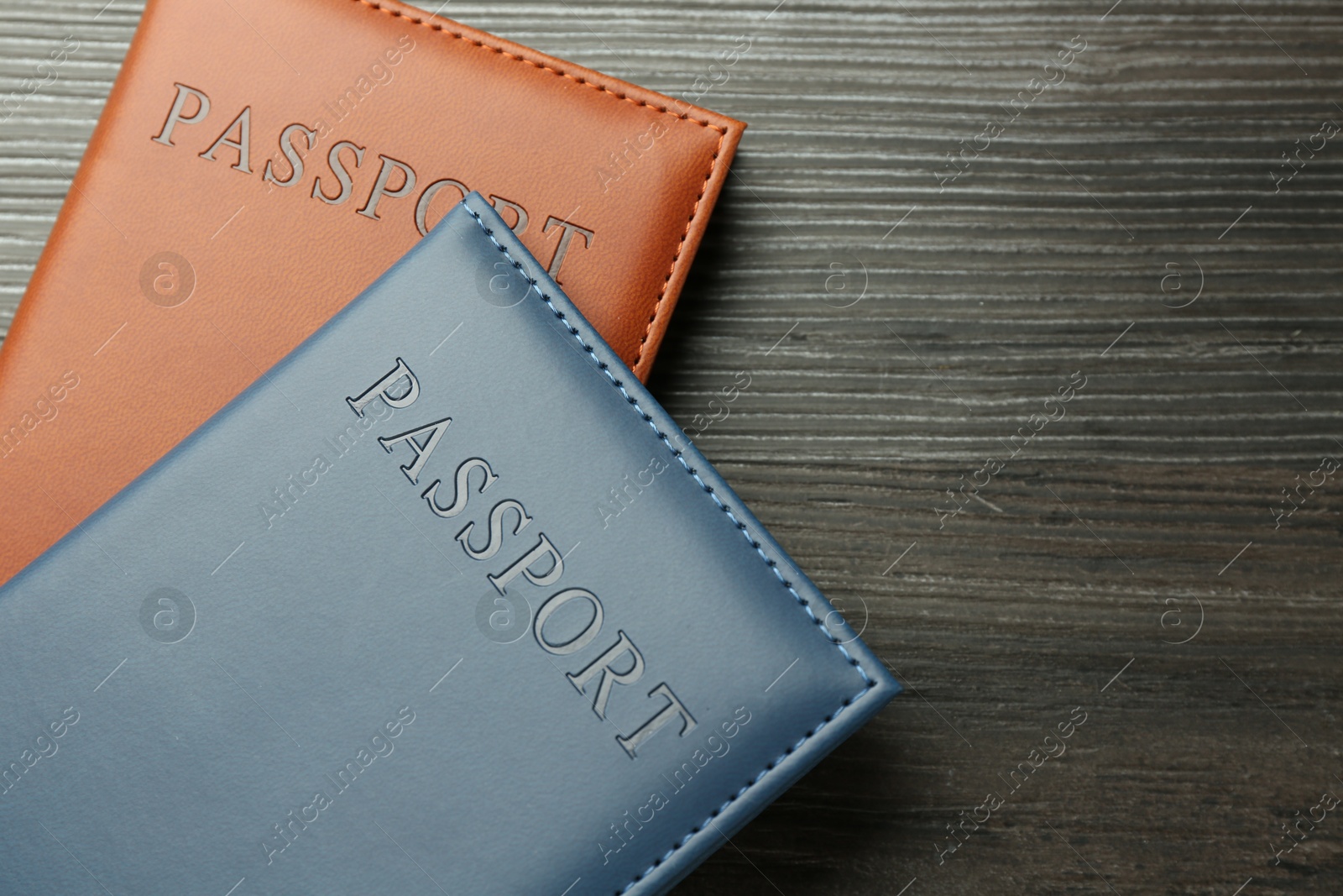 Photo of Passports in color covers on wooden table, top view. Space for text