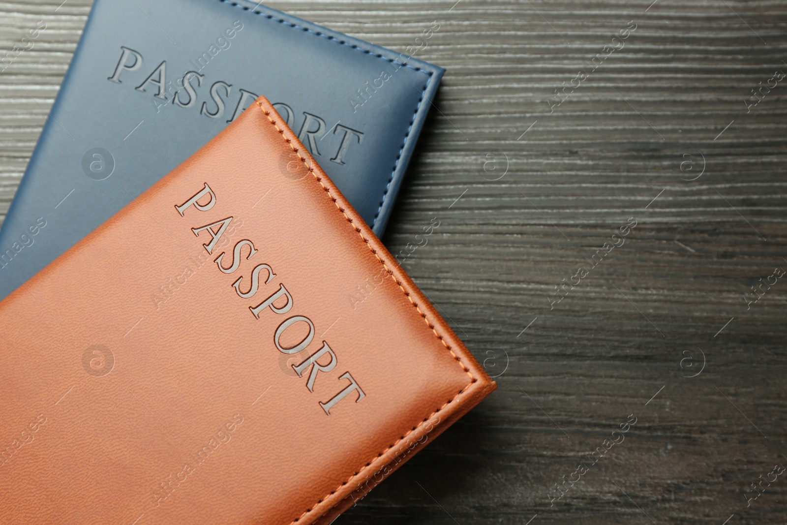 Photo of Passports in color covers on wooden table, top view. Space for text