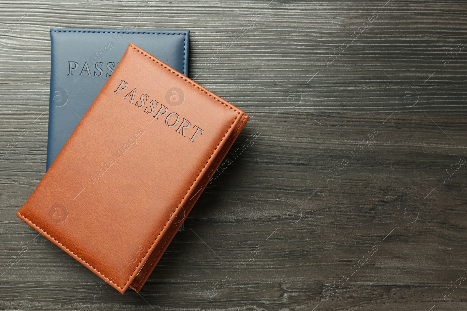 Photo of Passports in color covers on wooden table, top view. Space for text