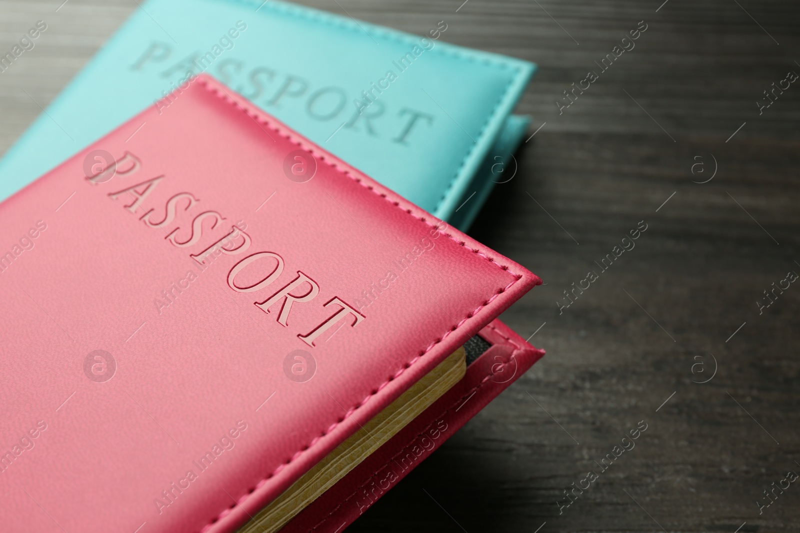 Photo of Passports in color covers on wooden table, closeup