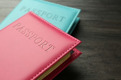 Photo of Passports in color covers on wooden table, closeup