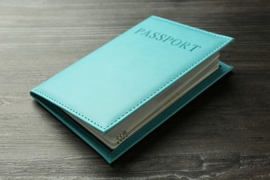 Photo of Passport in light blue cover on wooden table, closeup