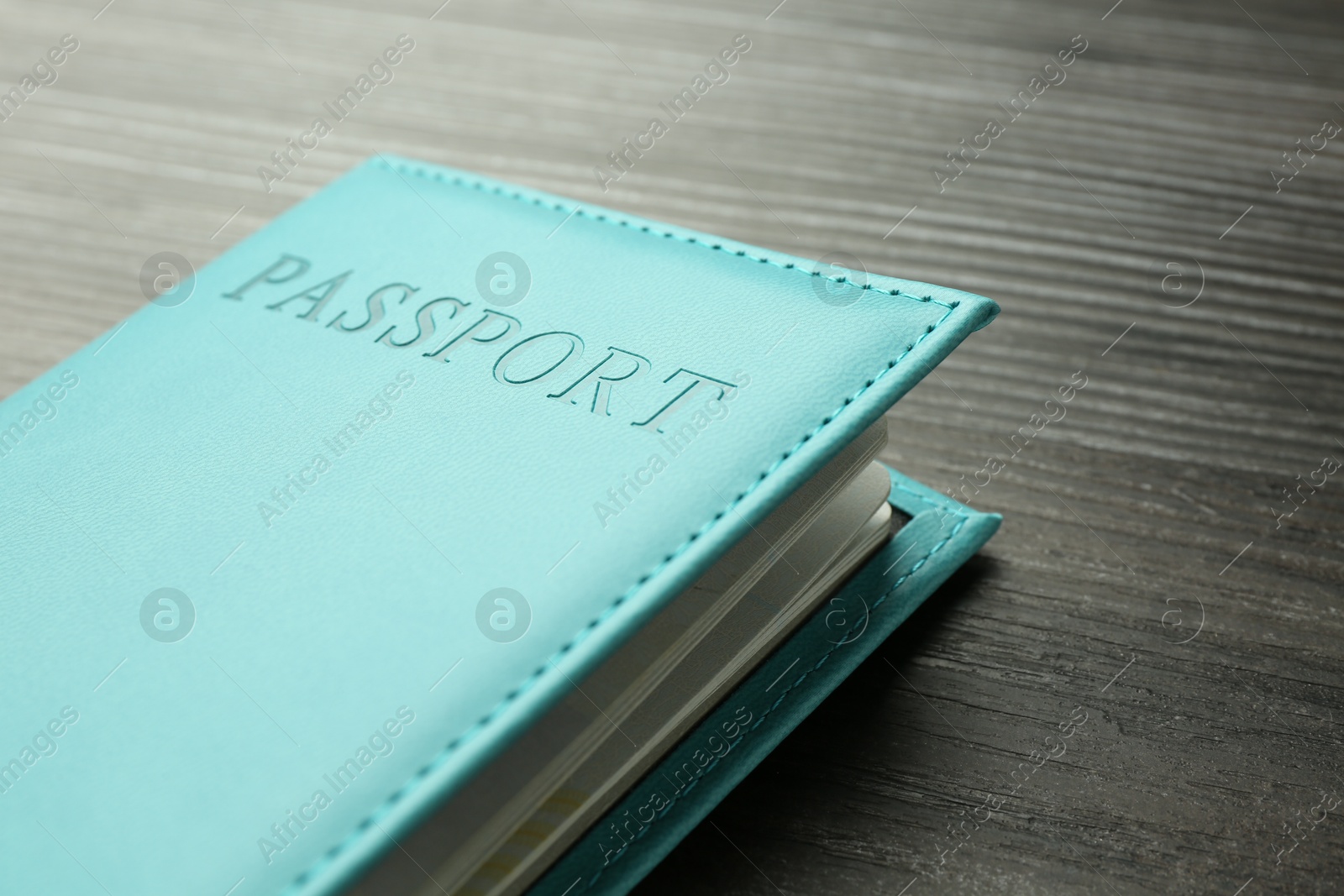 Photo of Passport in light blue cover on wooden table, closeup