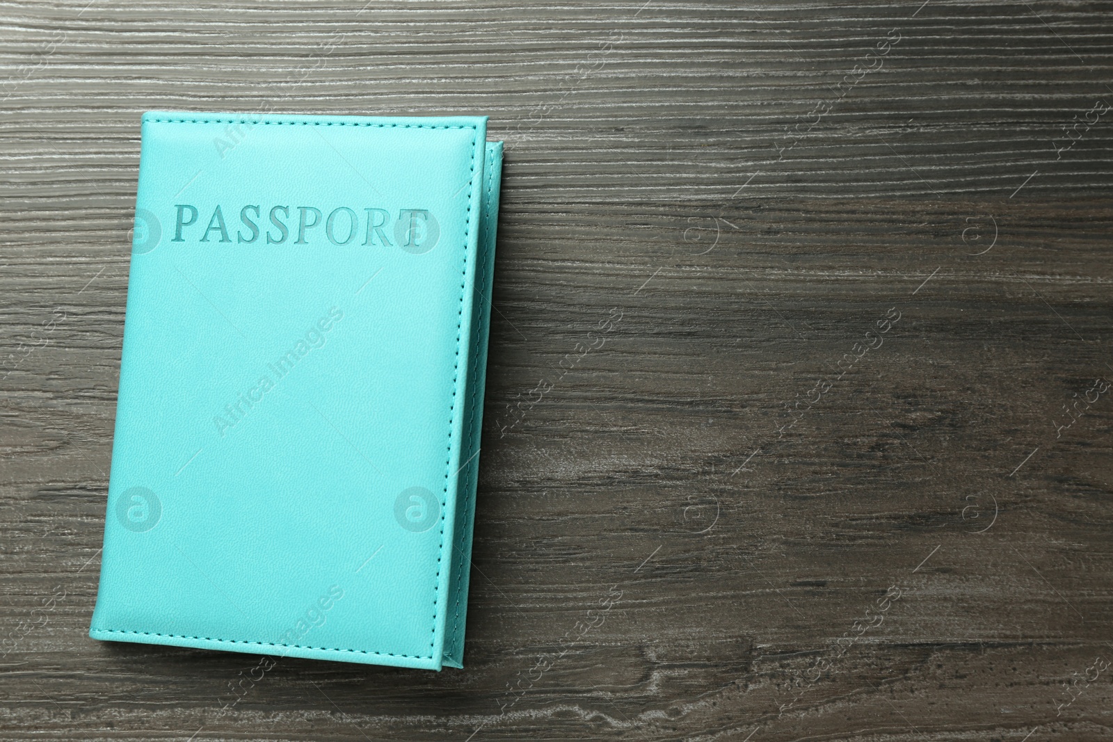 Photo of Passport in light blue cover on wooden table, top view. Space for text