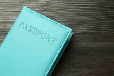 Photo of Passport in light blue cover on wooden table, top view. Space for text