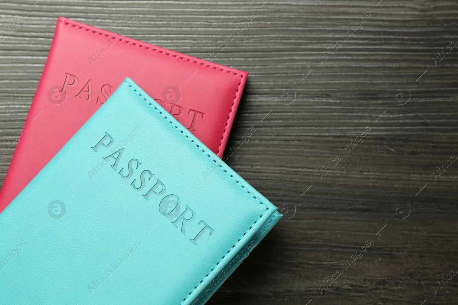 Photo of Passports in color covers on wooden table, top view. Space for text